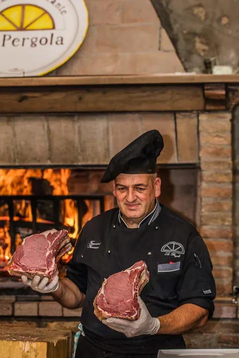 Lo chef mostra le bistecche da cuocere alla brace