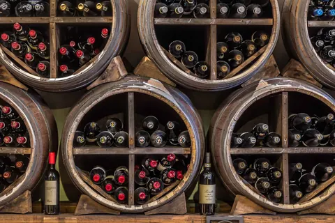 Botti in legno con le bottiglie dell'enoteca de La Pergola