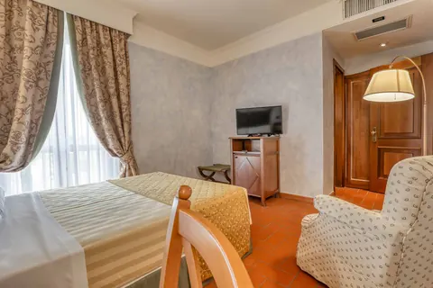 Camera dell'Hotel La Pergola con poltrona e TV