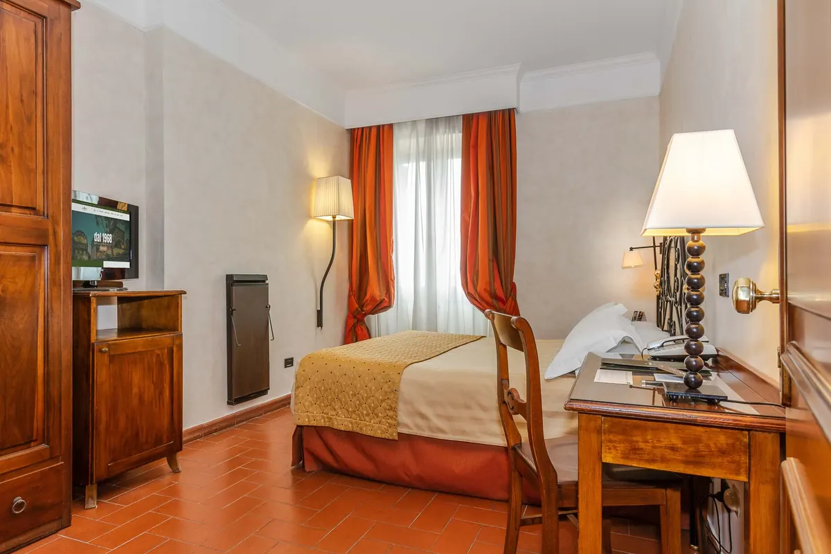 Camera dell'Hotel La Pergola con scrivania e tende rosse