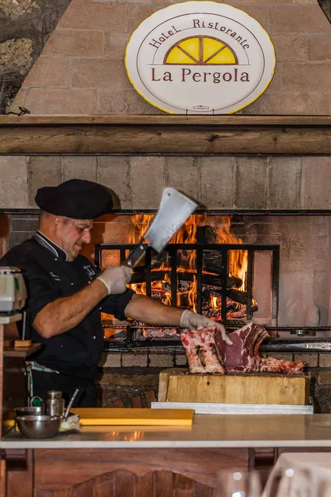 Lo chef taglia la carne davanti al camino a legna