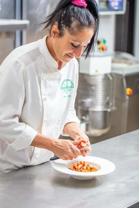 La chef impiatta la pasta al pomodoro