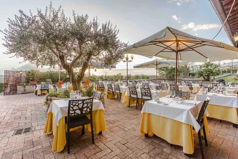 Terrazza esterna del ristorante con ulivi e ombrelloni